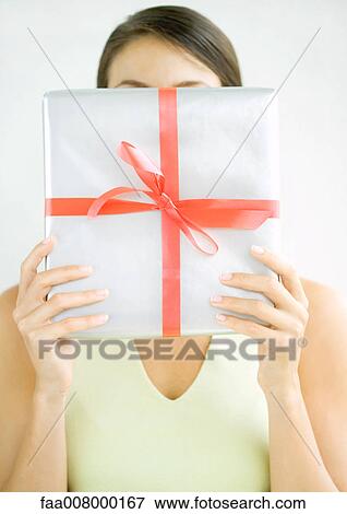 Stock Photo - Woman holding present in front of face. Fotosearch