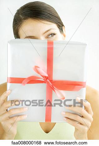 Stock Photo - Woman holding present in front of face. Fotosearch