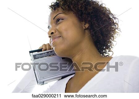 Woman holding radio on shoulder, smiling, looking away, low angle view View Large Photo Image Stock Image - Woman holding radio on shoulder, smiling, looking away, low angle view. Fotosearch