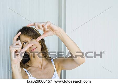 Woman holding up finger frame, looking up View Large Photo Image Stock Photo - Woman holding up finger frame, looking up. Fotosearch