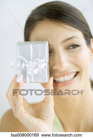 Woman holding up present in front of eye View Large Photo Image Stock Photo - Woman holding up present in front of eye. Fotosearch