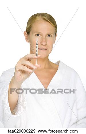 Woman in bathrobe holding up syringe, looking at camera View Large Photo Image Stock Photo - Woman in bathrobe holding up syringe, looking at camera. Fotosearch