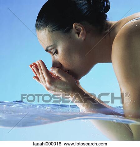 Woman in water cupping hands to face View Large Photo Image Stock Photograph - Woman in water cupping hands to face. Fotosearch