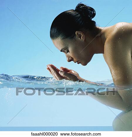 Woman kneeling in water, cupping hands to face View Large Photo Image Stock Image - Woman kneeling in water, cupping hands to face. Fotosearch