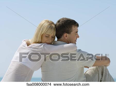 Woman leaning head on man's shoulder, sea in background View Large Photo Image Picture - Woman leaning head on man's shoulder, sea in background. Fotosearch