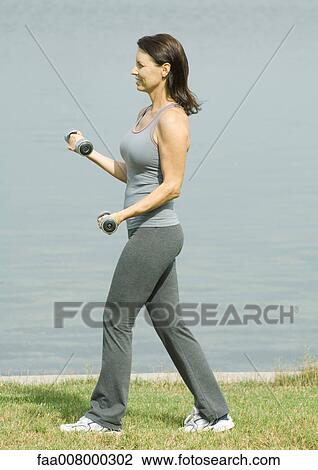 Woman lifting weights near edge of water View Large Photo Image Stock Image - Woman lifting weights near edge of water. Fotosearch