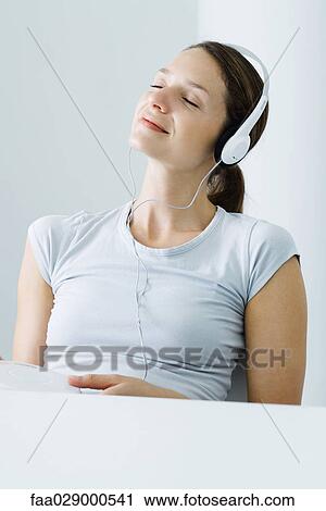 Woman listening to headphones, eyes closed, smiling View Large Photo Image Stock Image - Woman listening to headphones, eyes closed, smiling. Fotosearch