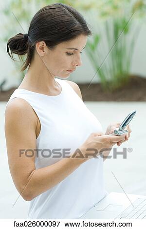 Woman looking down at cell phone, side view View Large Photo Image Stock Photo - Woman looking down at cell phone, side view. Fotosearch