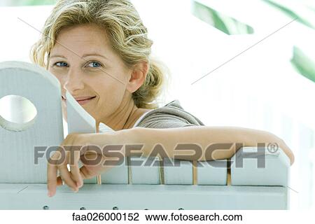 Woman looking over back of bench at camera, smiling View Large Photo Image Stock Image - Woman looking over back of bench at camera, smiling. Fotosearch