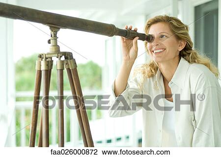 Woman looking through telescope, smiling, close-up View Large Photo Image Stock Image - Woman looking through telescope, smiling, close-up. Fotosearch