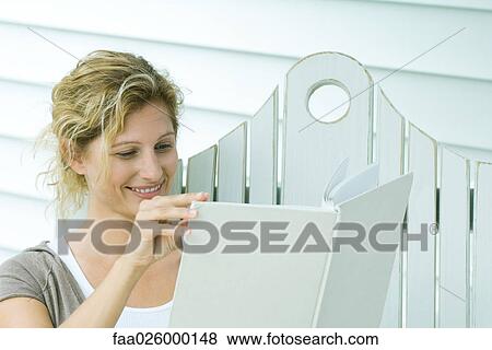 Woman on bench reading book, smiling, close-up View Large Photo Image Stock Photo - Woman on bench reading book, smiling, close-up. Fotosearch