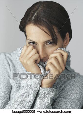 Stock Photography - Woman pulling up sweater over mouth, portrait. Fotosearch