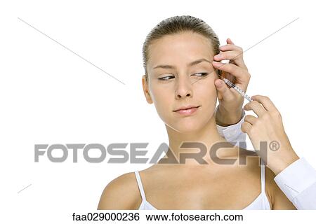 Stock Photograph - Woman receiving Botox injection, looking at syringe. Fotosearch