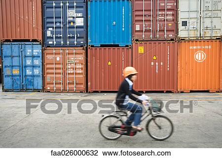 Woman riding bicycle past stacked metal storage units, side view View Large Photo Image Stock Image - Woman riding bicycle past stacked metal storage units, side view. Fotosearch