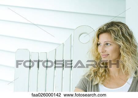 Woman sitting on bench, smiling, looking away View Large Photo Image Stock Image - Woman sitting on bench, smiling, looking away. Fotosearch