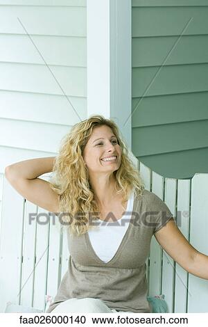Woman sitting on bench with hand behind head, smiling, looking away View Large Photo Image Stock Image - Woman sitting on bench with hand behind head, smiling, looking away. Fotosearch