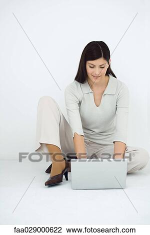 Woman sitting on the ground, using laptop computer, smiling View Large Photo Image Stock Image - Woman sitting on the ground, using laptop computer, smiling. Fotosearch