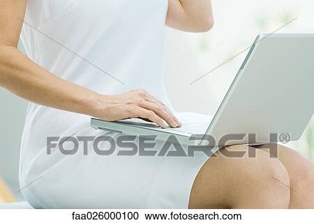 Woman sitting, using laptop computer, cropped view View Large Photo Image Stock Image - Woman sitting, using laptop computer, cropped view. Fotosearch