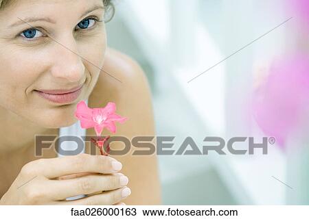 Woman smelling flower, smiling at camera, cropped View Large Photo Image Stock Image - Woman smelling flower, smiling at camera, cropped. Fotosearch