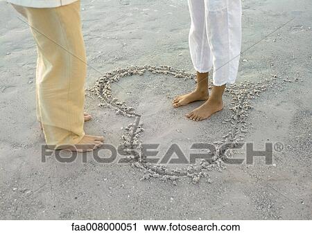 Woman standing inside heart drawn on beach, facing man, low section View Large Photo Image Stock Image - Woman standing inside heart drawn on beach, facing man, low section. Fotosearch