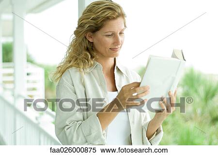 Woman standing on porch, reading book, close-up View Large Photo Image Stock Photography - Woman standing on porch, reading book, close-up. Fotosearch