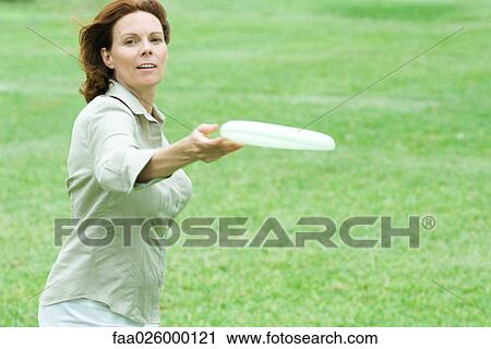 Woman throwing plastic disc, smiling at camera View Large Photo Image Stock Image - Woman throwing plastic disc, smiling at camera. Fotosearch