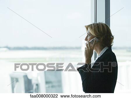 Woman using cell phone in airport, looking out window View Large Photo Image Stock Image - Woman using cell phone in airport, looking out window. Fotosearch