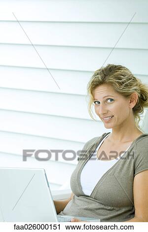 Woman using laptop computer, smiling at camera View Large Photo Image Stock Image - Woman using laptop computer, smiling at camera. Fotosearch