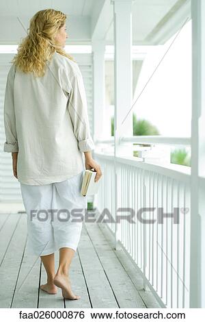 Woman walking on porch, carrying book, rear view View Large Photo Image Stock Photograph - Woman walking on porch, carrying book, rear view. Fotosearch