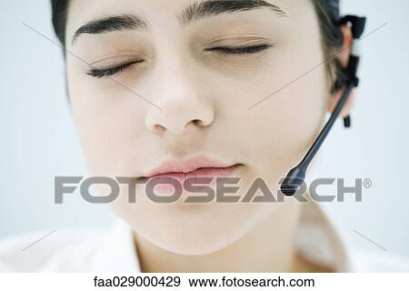 Woman wearing headset, closing eyes, close-up of face View Large Photo Image Stock Photo - Woman wearing headset, closing eyes, close-up of face. Fotosearch