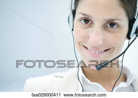Stock Image - Woman wearing headset, smiling at camera. Fotosearch