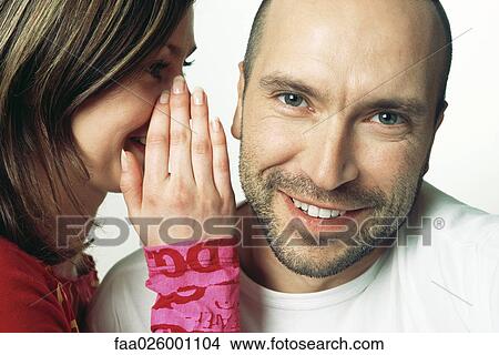 Woman whispering in man's ear, man smiling at camera View Large Photo Image Picture - Woman whispering in man's ear, man smiling at camera. Fotosearch