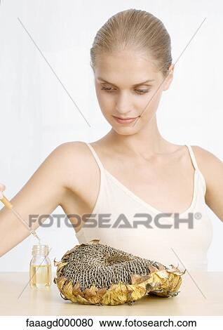 Stock Image - Woman with dried sunflower head and essential oil. Fotosearch