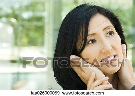 Stock Photo - Woman with husband's hands holding her face, cropped view. Fotosearch
