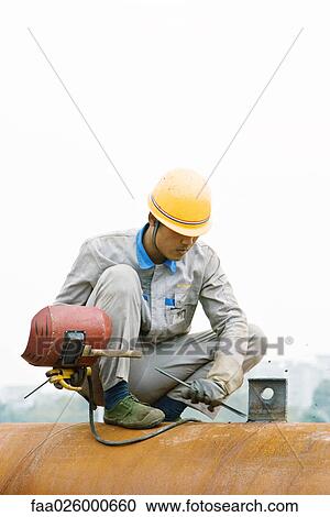 Worker crouching on metal pipe, holding welding mask, looking down View Large Photo Image Stock Image - Worker crouching on metal pipe, holding welding mask, looking down. Fotosearch