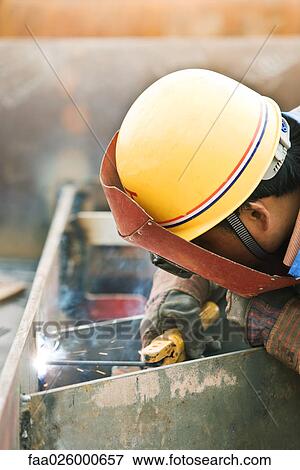 Stock Photo - Worker welding metal, side view, close-up. Fotosearch