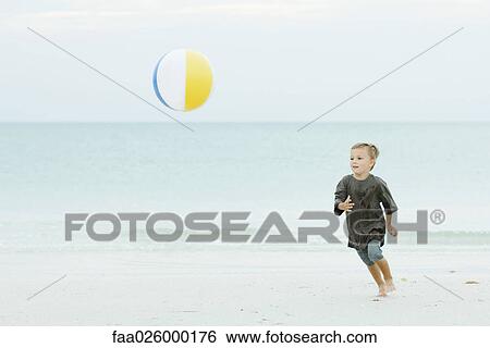 Young boy chasing beach ball at the beach View Large Photo Image Stock Photograph - Young boy chasing beach ball at the beach. Fotosearch