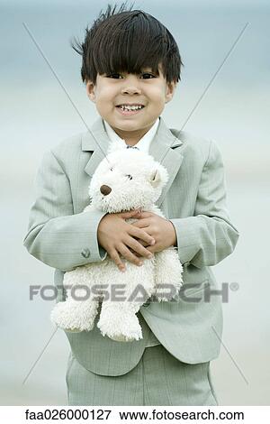 Young boy dressed in suit, holding teddy bear, smiling at camera View Large Photo Image Stock Photo - Young boy dressed in suit, holding teddy bear, smiling at camera. Fotosearch