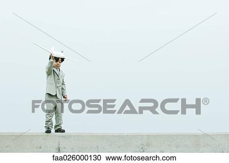 Young boy dressed in suit, holding up toy airplane View Large Photo Image Stock Image - Young boy dressed in suit, holding up toy airplane. Fotosearch