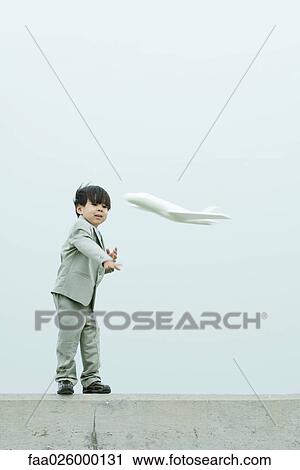 Young boy dressed in suit, throwing toy airplane View Large Photo Image Stock Image - Young boy dressed in suit, throwing toy airplane. Fotosearch