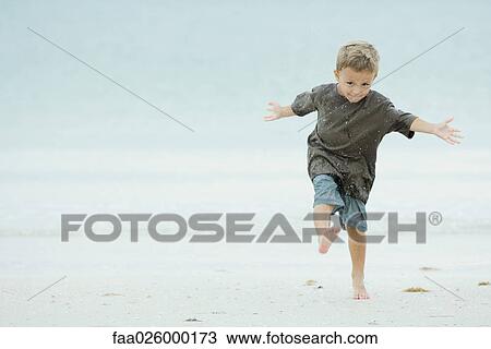 Young boy kicking sand at the beach, full length View Large Photo Image Stock Image - Young boy kicking sand at the beach, full length. Fotosearch