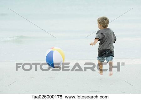 Young boy running after beach ball at the beach, rear view View Large Photo Image Stock Photography - Young boy running after beach ball at the beach, rear view. Fotosearch