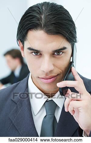 Young businessman using cellphone, smiling at camera, portrait View Large Photo Image Picture - Young businessman using cellphone, smiling at camera, portrait. Fotosearch