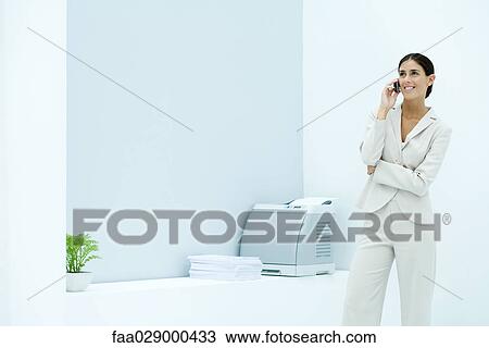 Young businesswoman using cell phone in office, smiling View Large Photo Image Stock Image - Young businesswoman using cell phone in office, smiling. Fotosearch
