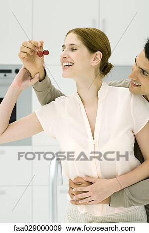 Young couple in kitchen, man feeding woman cherries View Large Photo Image Stock Photo - Young couple in kitchen, man feeding woman cherries. Fotosearch