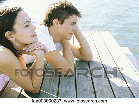 Young couple lying on dock, looking at distance View Large Photo Image Stock Photo - Young couple lying on dock, looking at distance. Fotosearch