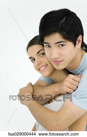 Young couple smiling at camera, embracing, portrait View Large Photo Image Picture - Young couple smiling at camera, embracing, portrait. Fotosearch