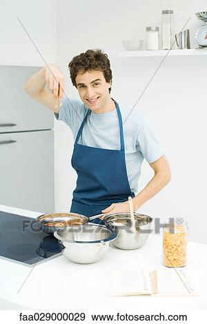 Young man cooking, smiling at camera View Large Photo Image Stock Photo - Young man cooking, smiling at camera. Fotosearch