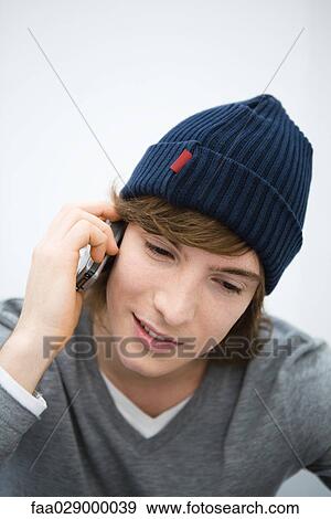 Young man in knit hat using cell phone, looking down, close-up View Large Photo Image Stock Photo - Young man in knit hat using cell phone, looking down, close-up. Fotosearch