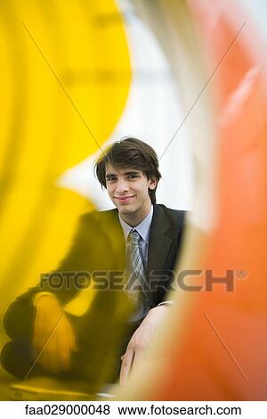 Young man in suit smiling at camera, viewed through electric fan View Large Photo Image Stock Photo - Young man in suit smiling at camera, viewed through electric fan. Fotosearch